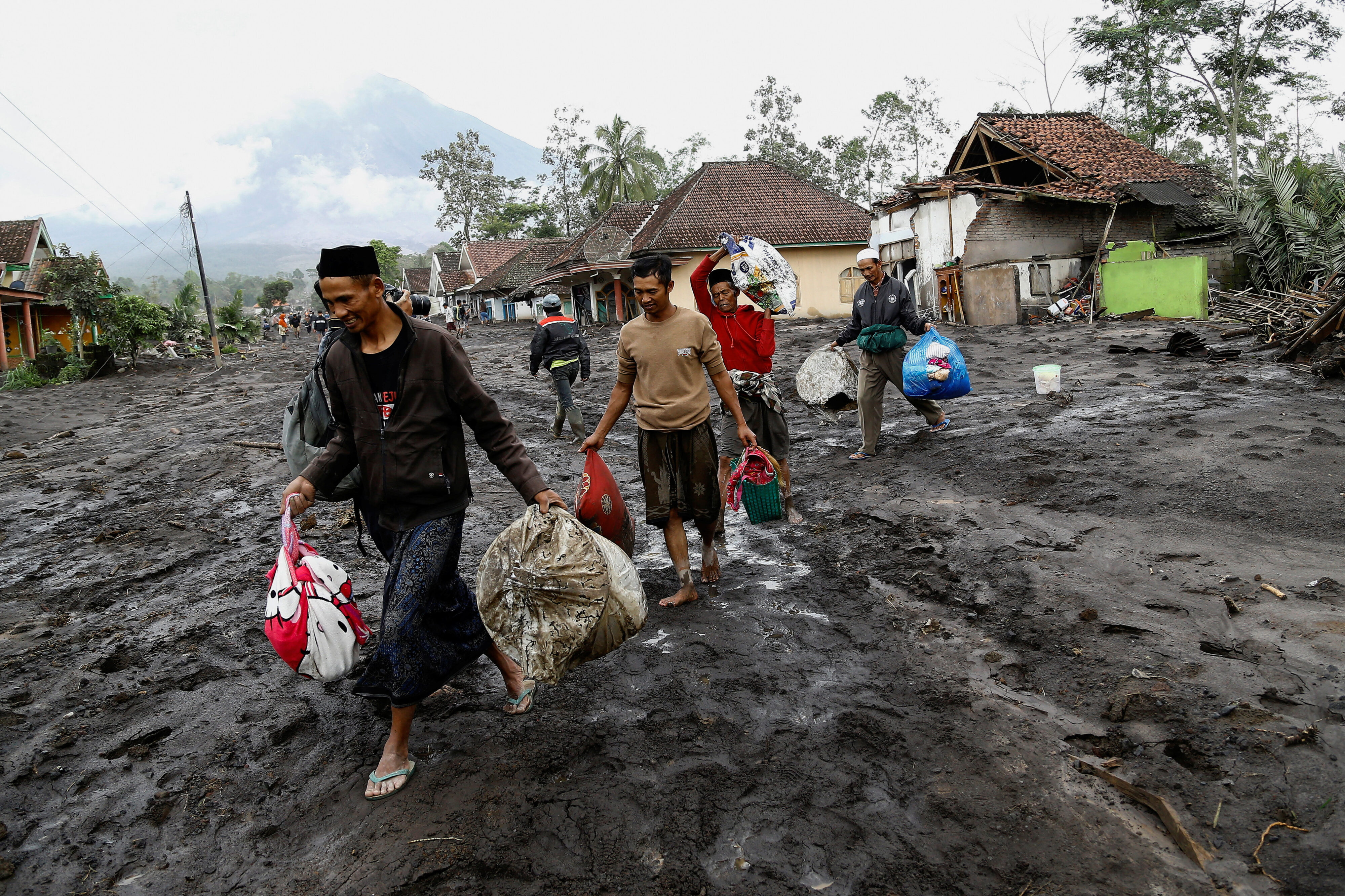 Local residents carry valuable goods from their houses in an area affected by an overnight Mount Semeru volcano eruption. Reuters