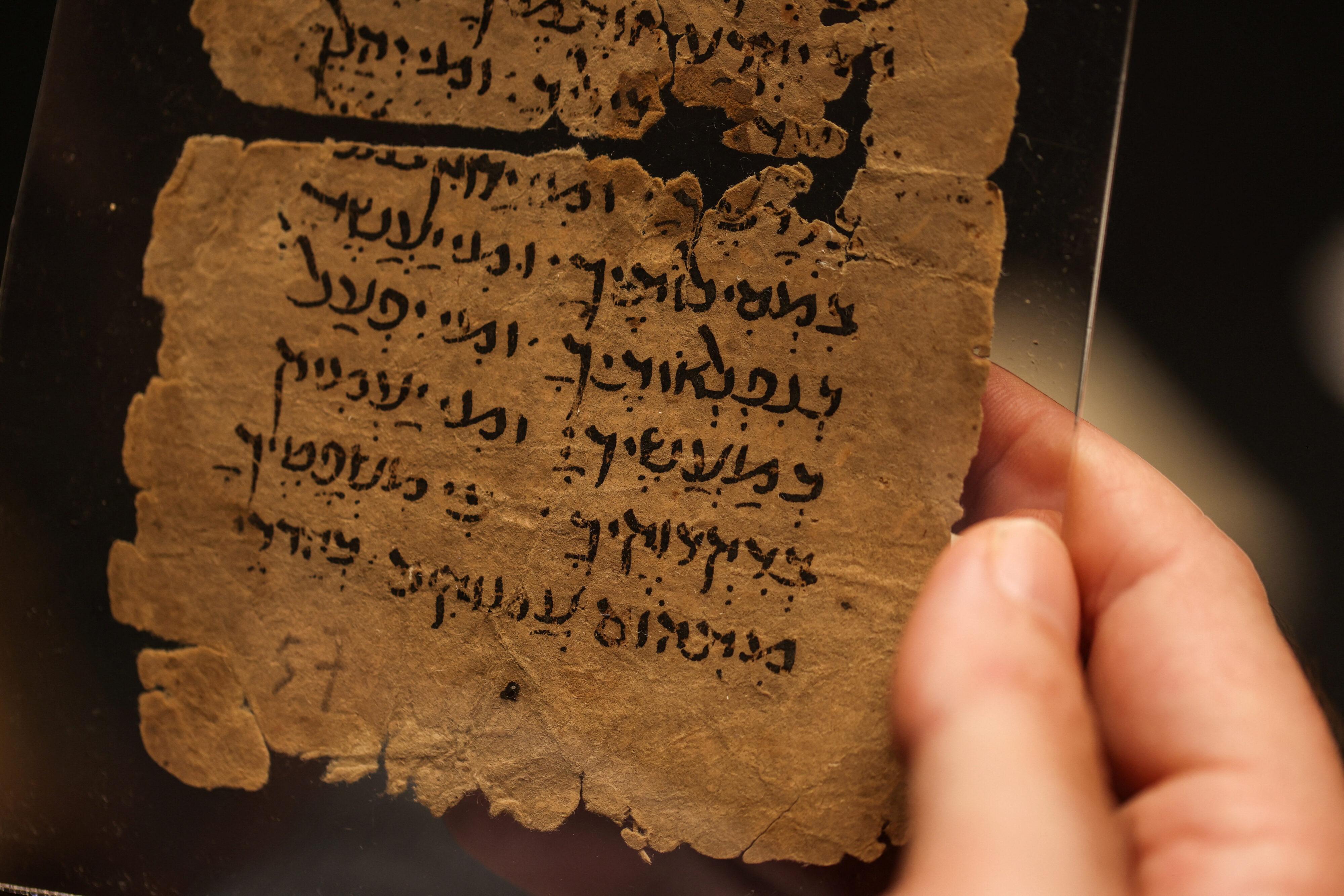 A researcher holds up a 12th century fragment of a Yom Kippur liturgy in Jerusalem. Reuters